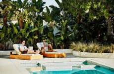 Gay couple working on laptop and digital tablet while relaxing by pool