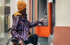 woman in a wheelchair using atm to withdraw money