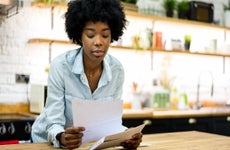 Black woman at home reading a letter in the mail