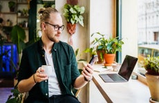 man looking at phone while having coffee in cafe