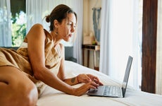 woman working on her laptop while relaxing on bed