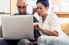 Couple looking at laptop while sitting on sofa at home