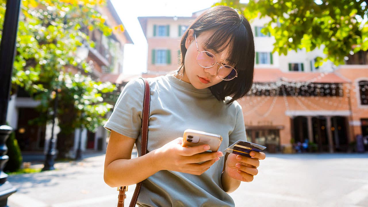 woman looking at phone and credit card