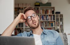 Man on laptop looking to side contemplatively