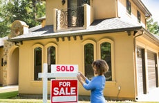 Real estate agent placing a "sold" sign on a home