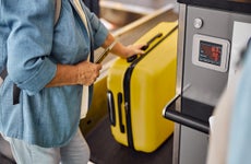 older woman picking up luggage