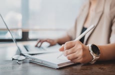 Woman working with laptop computer and documents.Hands at work with Digital Technology.Working on desk environment.Analog working with documents.