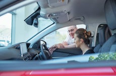 Salesman demonstrating car controls to customer in car dealership