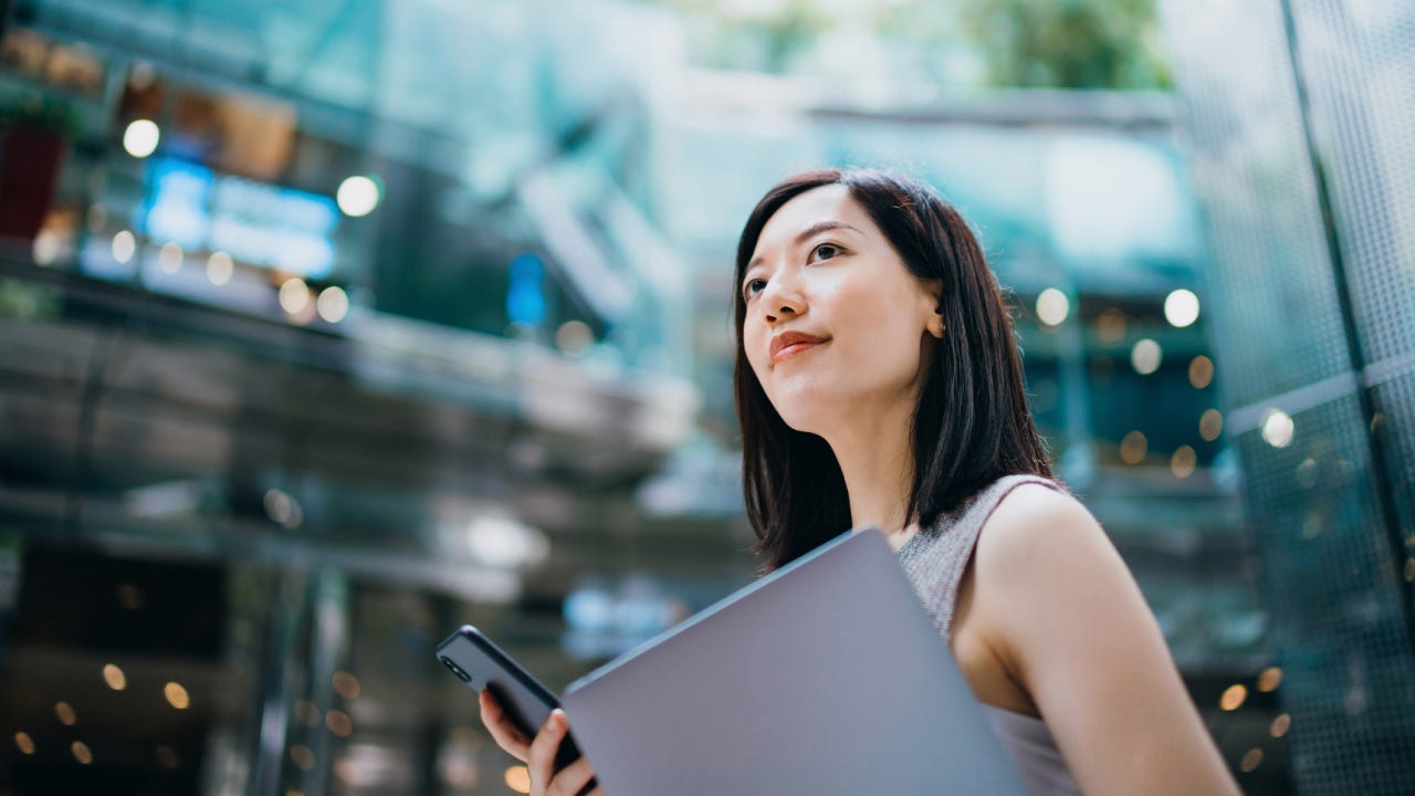 businesswoman carrying smartphone and laptop, commuting to work