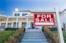 white suburban house with red for sale sign looking up front steps