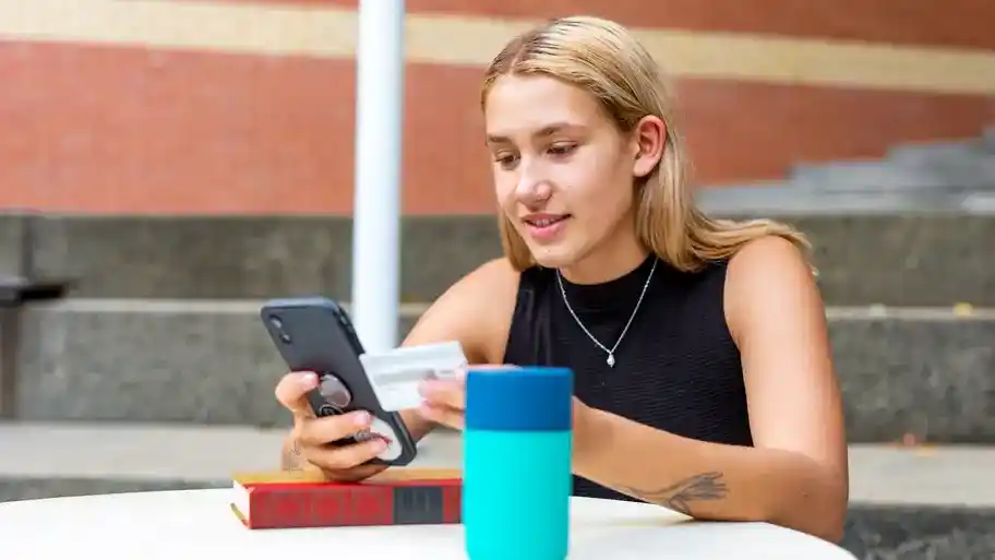 young women on her phone and holding a credit card