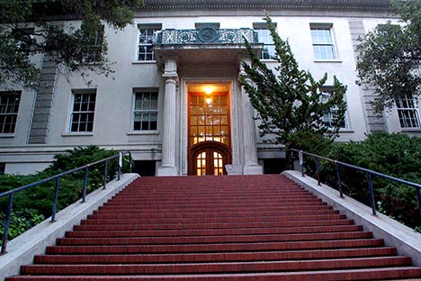 Looking from the bottom of a red stairway to the grand entrance with columns and portico