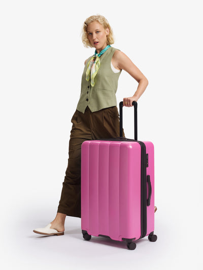 CALPAK raspberry large luggage made from an ultra-durable polycarbonate shell and expandable by up to 2