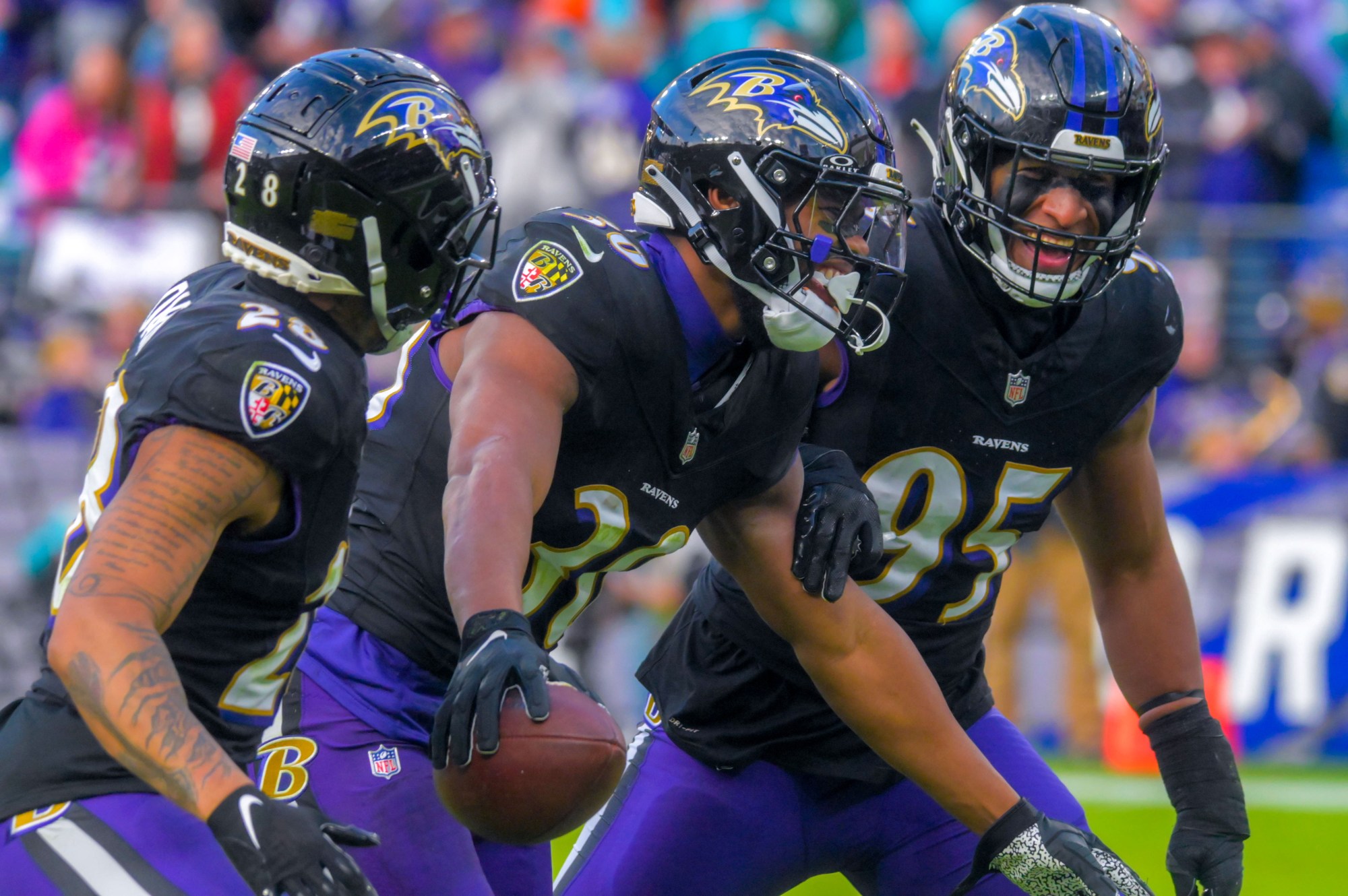 Baltimore Ravens inside linebacker Trenton Simpson (30) holds the football, celebrating his interception of a Miami Dolphins quarterback Tua Tagovailoa pass with cornerback Ronald Darby (28) and outside linebacker Tavius Robinson (95) during the fourth quarter of an AFC matchup of NFL football in Baltimore. The Ravens became the AFC North champions, securing home field advantage throughout the playoffs with their 56-19 drubbing of Miami. (Karl Merton Ferron/Baltimore Sun Staff)