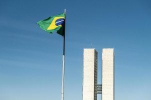 The Brazilian flag flying in front of the National Congress buildings