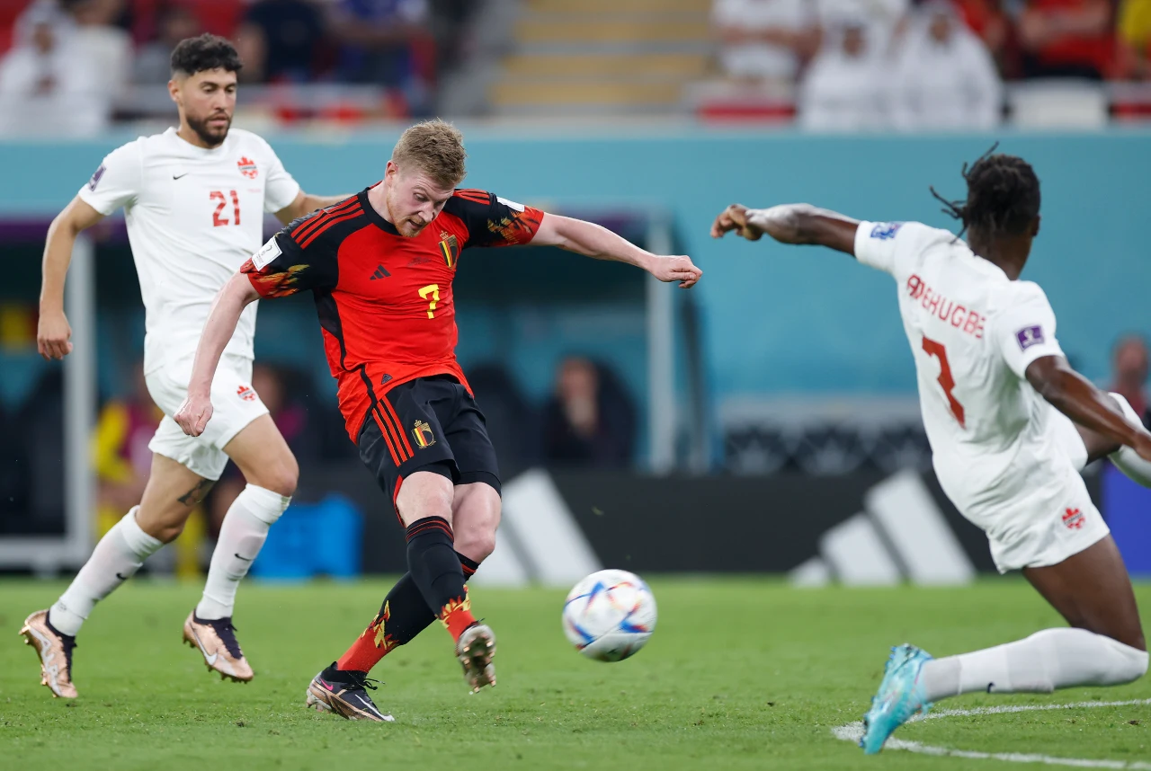 Belgium midfielder Kevin De Bruyne (7) shoots in front of Canada defender Sam Adekugbe (3) during the second half of a group stage match during the 2022 FIFA World Cup at Ahmad Bin Ali Stadium.