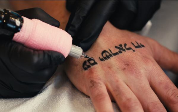 A tattoo artist tattooing a person's hand