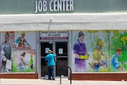 FILE - In this May 7, 2020 file photo, a person looks inside the closed doors of the Pasadena Community Job Center in Pasadena, Calif., during the coronavirus outbreak. California's unemployment rate continued to climb in May, reaching 16.3% as businesses continued to lay people off because of a state-at-home order aimed at slowing the spread of the coronavirus that has wrecked the state's economy.