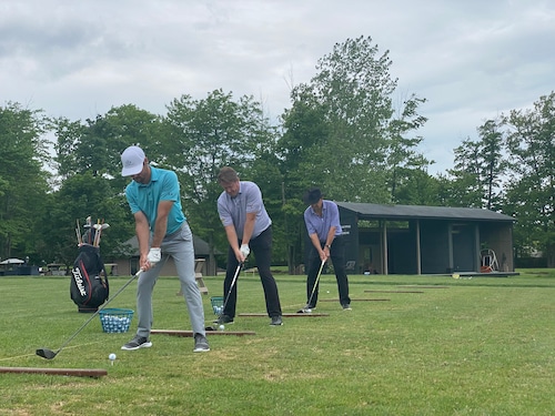 Three golfers teeing up on a course