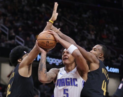 Orlando Magic forward Paolo Banchero drives towards the basket between the defense of Cleveland Cavaliers center Jarrett Allen (L) and Cleveland Cavaliers forward Evan Mobley