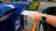 In this Tuesday, Aug. 18, 2020, file photo, a person drops applications for mail-in-ballots into a mail box in Omaha, Neb. A U.S. judge on Thursday, Sept. 17, 2020, blocked controversial Postal Service changes that have slowed mail nationwide. The judge called them "a politically motivated attack on the efficiency of the Postal Service" before the November election. (AP Photo/Nati Harnik, File)