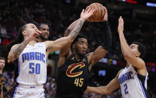 Cleveland Cavaliers guard Donovan Mitchell secures possession of a rebound from Orlando Magic guard Cole Anthony (L) and Orlando Magic guard Caleb Houstan in the second half