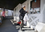 Stephanie Sgro, a youth program specialist at University Settlement, hangs a bag of supplies on a door handle on E. 55th Street in the Slavic Village neighborhood of Cleveland on Friday. Sgro, along with workers and volunteers from the University Settlement, are passing out care packages in Slavic Village to help with the coronavirus pandemic. The University Settlement packed about 300 supply bags that included things such as soap, hand sanitizer and a first aid kit. (Lisa DeJong/The Plain Dealer)