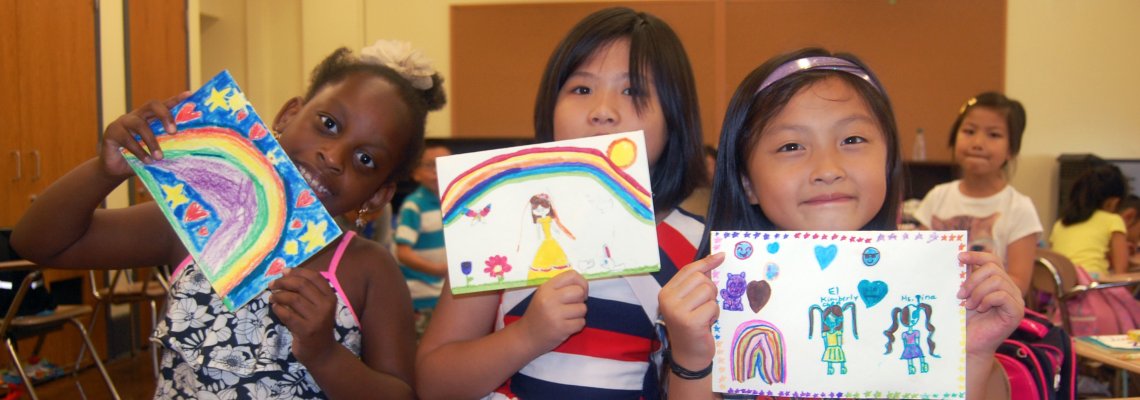 Three young girls showing their artwork