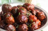 A metal pie pan filled with crockpot meatballs.