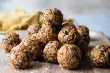 A stack of energy balls on a wooden cutting board.