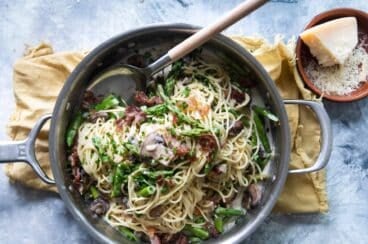 Pasta with peas and prosciutto in a silver skillet.