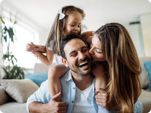 Family sitting on couch, wife kissing husband on cheek