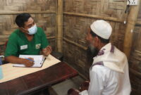 Refugee from Rohingya talking with MSF's medical assistant, Robiul Awal, in a healthcare setting.