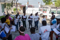 18 MSF team members standing during a debrief at a mobile clinic in Bel Air.