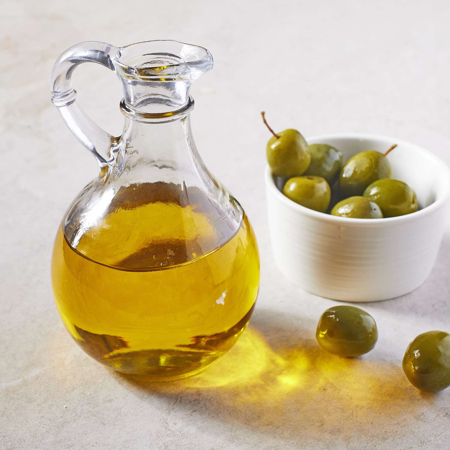 a bottle of Olive Oil beside a bowl of olives