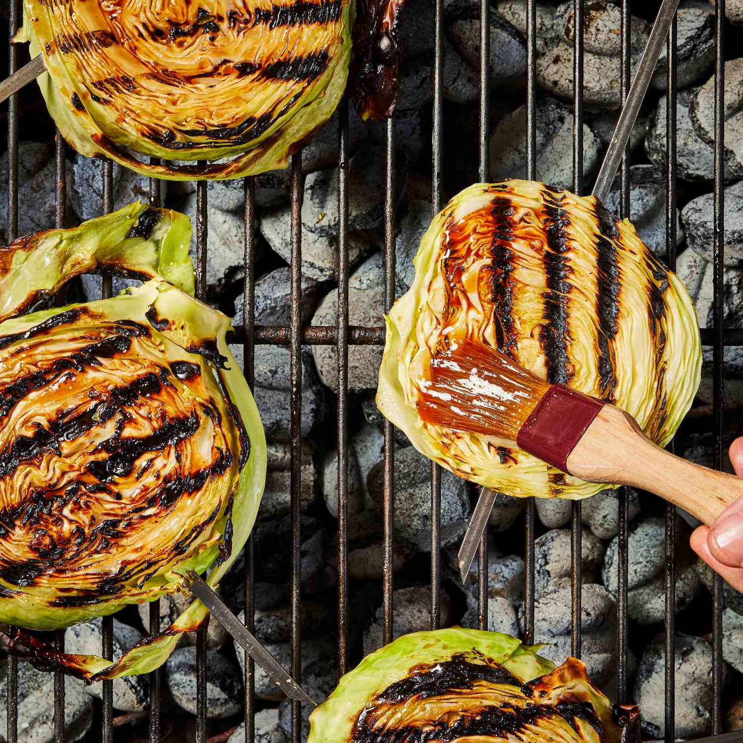 a photo of the cabbage getting sauce brushed on it while on the grill