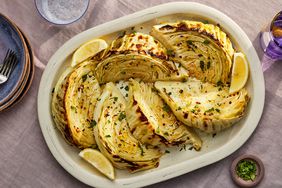 Roasted lemon-garlic cabbage wedges on a white serving plate, garnished with fresh parsley and lemon wedges