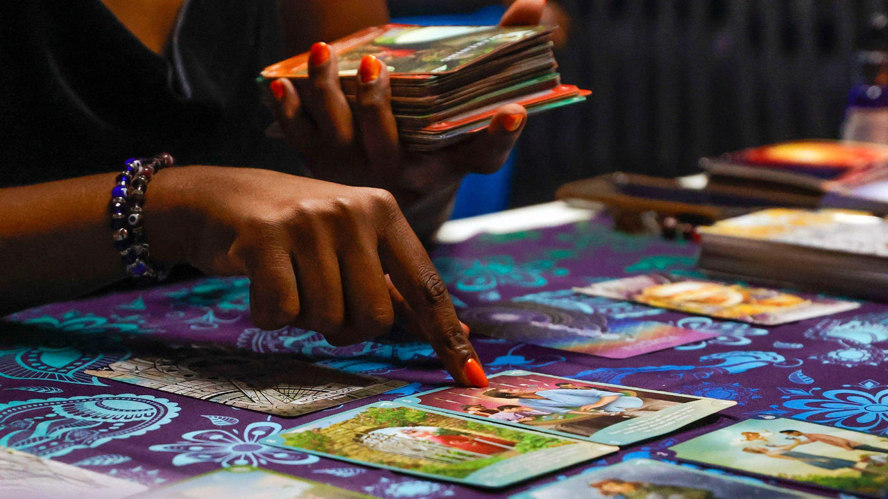 A tarot reader shows a tarot card during a reading.