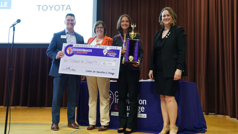 2nd place winner holding check and trophy.