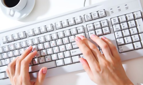 female hands typing on white computer keyboard on white desk