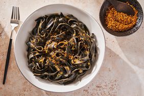 bowl of squid ink pasta with uni butter and small bowl of sukkah