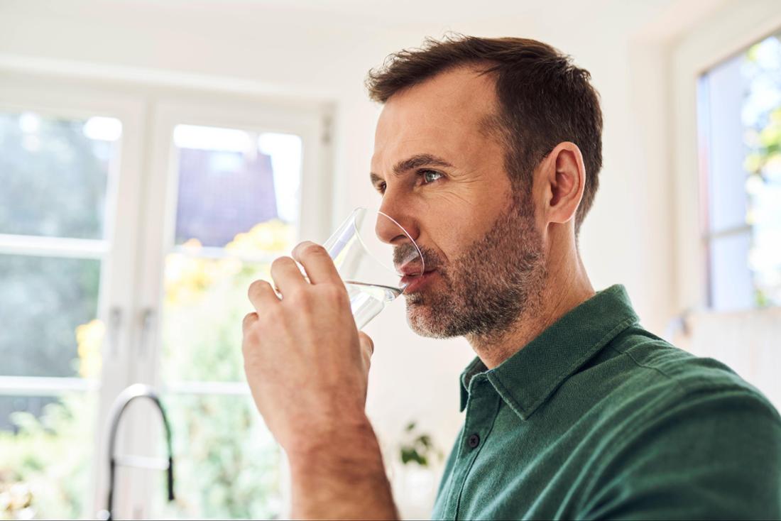 Man drinking glass of water standing in the kitchen model released, Symbolfoto