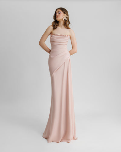 A strapless, straight cut blush long evening dress, with beading details on the bust line, and some draping details from the bust going down the waist.