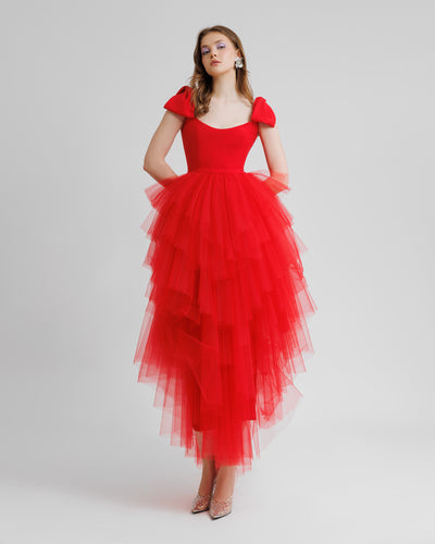 A long red evening dress with bow designs on the shoulders and asymmetrical rushed tulle layered skirt.