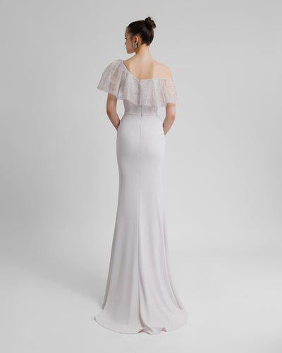 The back of an asymmetrical beaded mesh ruffled neckline slim-cut long evening dress in light lilac color.