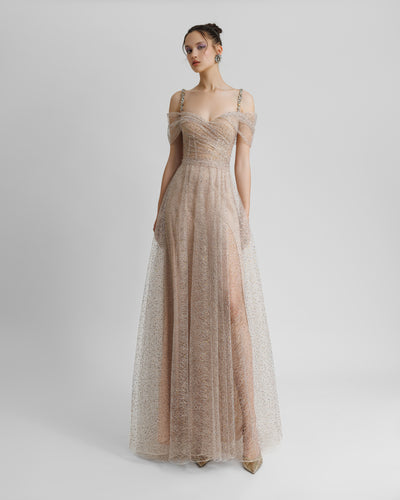 An off-the-shoulders embellished corseted champagne evening dress with draping on the waist, beaded straps, and a slit on the side.