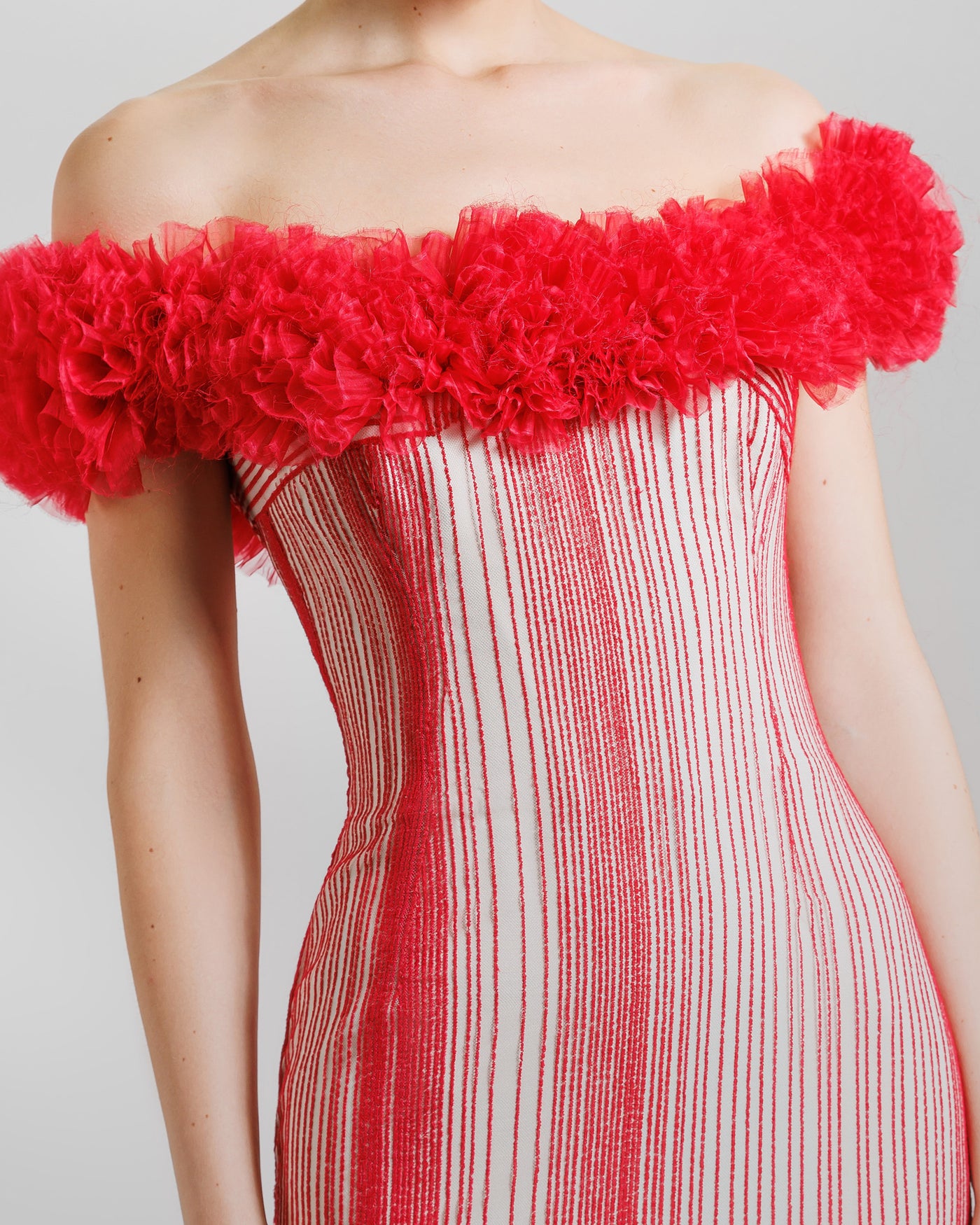 A close-up of an off-the-shoulders slim-cut red evening dress with rushed organza on the neckline.
