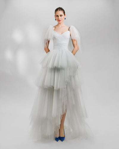 A fully ruffled grey tulle evening dress featuring a draped corset accentuating the waist, a sweetheart neckline, and an asymmetrical hemline. It also features beaded straps and ruffled tulle on the shoulders.