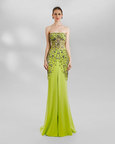 A fully embroidered strapless slim-cut long dress, made from bejeweled silver accessories. The corset is see through and the crepe skirt has beadings on the side hips, and a slit in the middle.