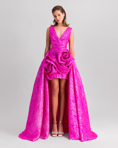 A deep v-neckline fuchsia evening dress featuring big draped flowers and a wide draped tail.